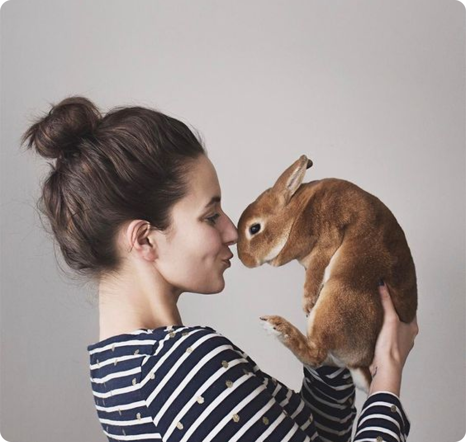 A woman snuggling a rabbit